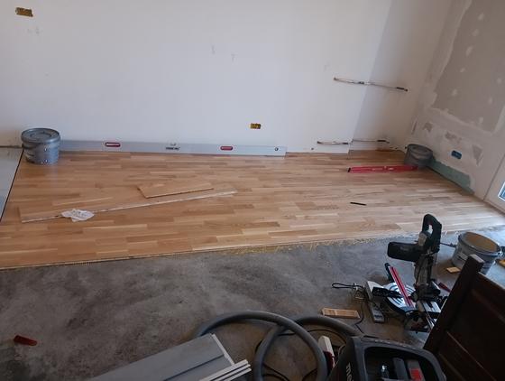 Laying the parquet, the first boards set along a batten and the level